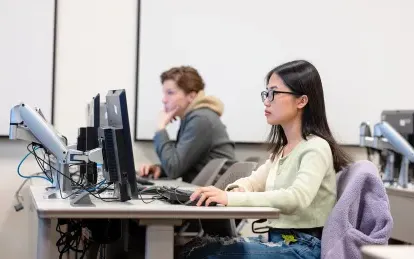 两个学生在教室里玩电脑 